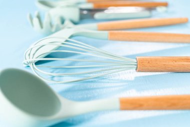 Mavi arka planda ahşap saplı yeni mavi silikon mutfak aletleri..