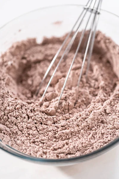 Mixing ingredients in a glass mixing bowl to bake chocolate bundt cake with chocolate frosting.