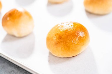 Parşömen kağıdıyla kaplanmış bir çarşafın üzerinde yumurta yıkama ile taze pişmiş yemek ruloları..