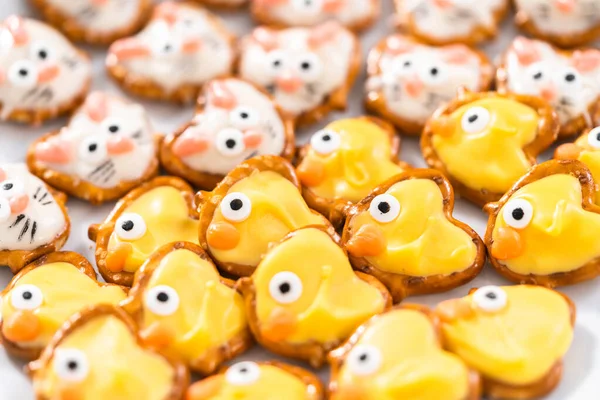 Easter chocolate-covered pretzel bunnies and ducklings on a white serving plate for the Easter table.