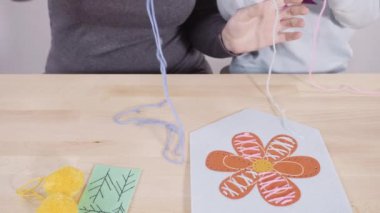 Küçük kız annesiyle el sanatları masasında dikiş dikmeyi öğreniyor..