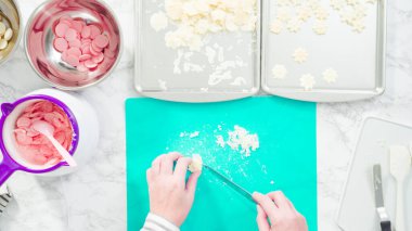 Düz yatıyordu. Adım adım. Fazla çikolatayı, kar taneleri şeklindeki çikolatalardan küçük bir mutfak bıçağıyla budamak..