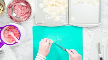 Düz yatıyordu. Adım adım. Fazla çikolatayı, kar taneleri şeklindeki çikolatalardan küçük bir mutfak bıçağıyla budamak..