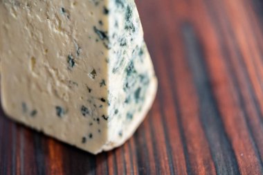 Koyu ahşap arka planda büyük bir dilim mavi peynir..