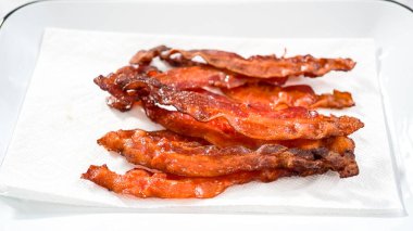 Adım adım. Beyaz tepside pişmiş pastırma şeritleri ve kağıt havlu..