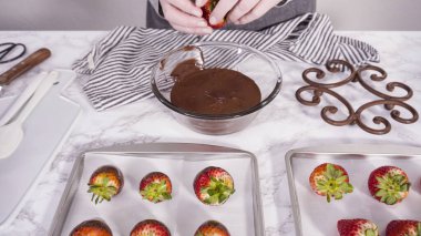 Adım adım. Çikolata kaplı çilek hazırlamak için organik çilekleri erimiş çikolatayla bir kaseye daldırmak..