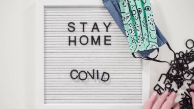 Düz yatıyordu. Evde Kal ve COVID-19 tabelasında ev yapımı yüz maskesi var..