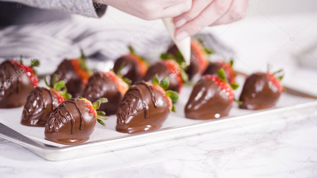 Step by step. Dipping organic strawberries into a bowl with melted chocolate to prepare chocolate covered strawberries.