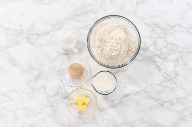 Düz yatıyordu. Mutfak masasında çörek pişirmek için gerekli malzemeler..