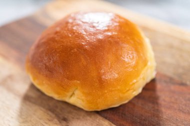 Odun kesme tahtasının üzerinde taze pişmiş çörekleri dilimliyorum..