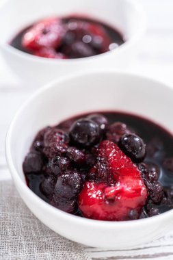 Ev yapımı böğürtlen kompostosu ahşap bir masada küçük beyaz kaselerde..