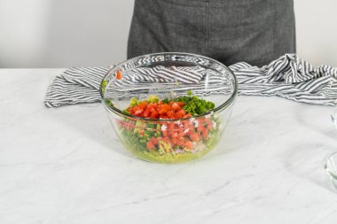 Klasik guacamole sosu yapmak için beyaz kesim tahtasındaki malzemeleri kesiyorum..