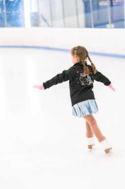 Küçük kız buz pateni pistinde artistik patinaj yapıyor..