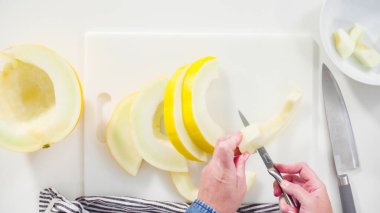 Adım adım. Düz yatıyordu. Beyaz kesme tahtasında kaygan altın çiğ taneli kavun.