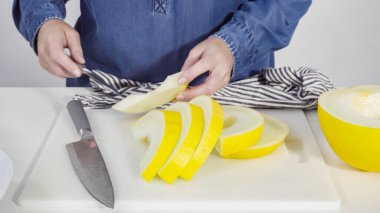 Adım adım. Beyaz kesme tahtasında kaygan altın çiğ taneli kavun.