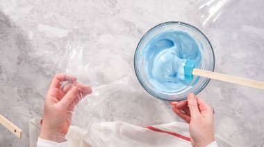 Düz yatıyordu. Adım adım. Tek boynuzlu at meringue kurabiyesi pişirmek için metal uçlu boru torbalarına krema karıştırılıyor..