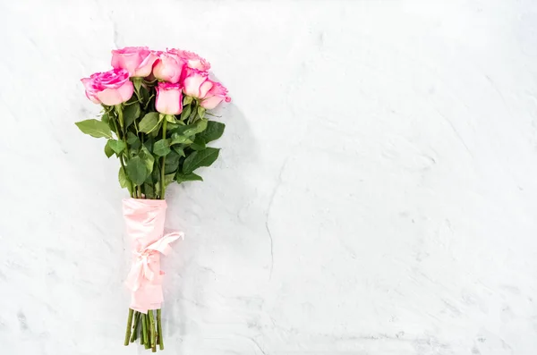 粉红玫瑰花束 用粉红包装纸包裹 混凝土背景上有粉红缎带 — 图库照片