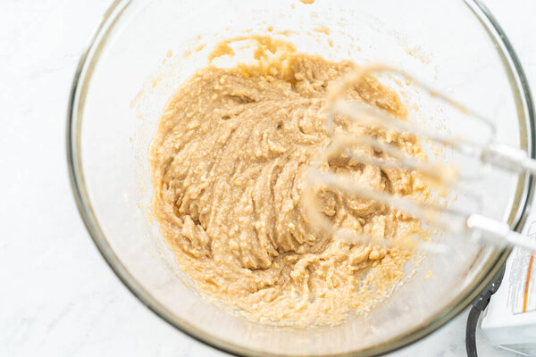 Смешивание ингредиентов в миске смешивания стекла для выпечки шоколадных крекеров.