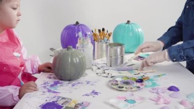 Anne ve kız, Cadılar Bayramı için deniz kızı temalı balkabakları süslüyor..