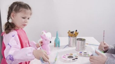 Evde resim dersinde kağıt heykel boyayan küçük bir kız..