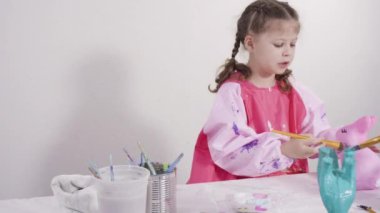 Evde resim dersinde kağıt heykel boyayan küçük bir kız..