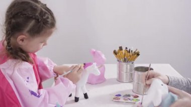 Evde resim dersinde kağıt heykel boyayan küçük bir kız..