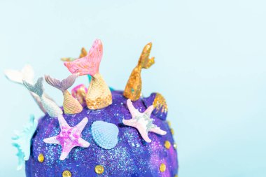 Cadılar Bayramı balkabakları deniz kızı kuyruğu, parıltı ve parlak elmaslarla süslenmiş mavi bir arka planda..