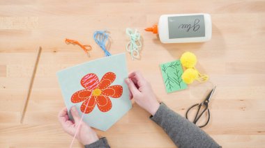 Anne çocuklara el sanatları masasında dikiş setiyle dikiş dikmeyi öğretiyor..