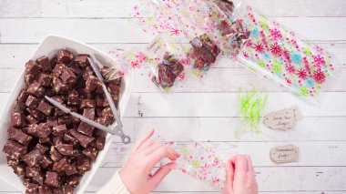 Düz yatıyordu. Adım adım. Ev yapımı macadamia şekerlemesi küçük hediye paketlerine konuyor..