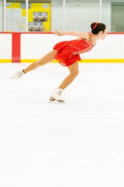 Genç kız buz pateni pistinde artistik patinaj yapıyor..