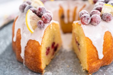 Dilimlenmiş limonlu kek. Şeker kızılcıkları ve limon dilimleri ile süslenmiş..