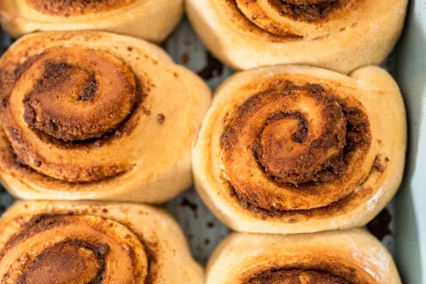 Freshly baked cinnamon rolls in a blue baking pan.