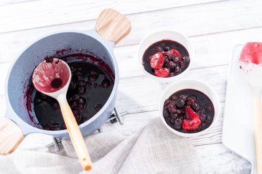 Donmuş böğürtlenlerin karışımını yapışmaz bir tencerede hazırlıyorum..