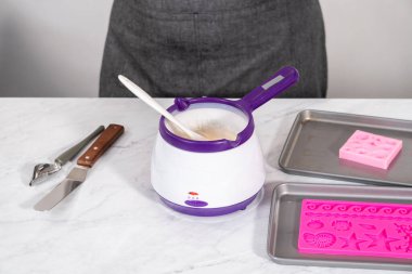 Deniz kızı keklerini hazırlamak için silikon çikolata kalıplarını erimiş beyaz çikolatayla dolduruyorum..