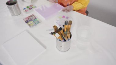 Uzak bir sanat projesi için annesiyle tuvale akrilik boyayla resim yapan küçük bir kız..