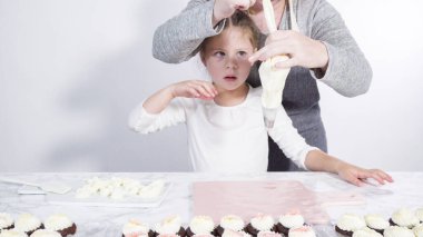 Adım adım. Küçük kız kesme tahtasına tereyağı kreması sürme alıştırması yapıyor.