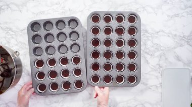 Düz yatıyordu. Adım adım. Mini çikolatalı kekler pişirmek için kek hamurunu mini kek kuyruklarına karıştırmak..