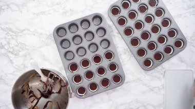 Düz yatıyordu. Adım adım. Mini çikolatalı kekler pişirmek için kek hamurunu mini kek kuyruklarına karıştırmak..