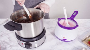 Adım adım. Çikolata parçacıkları eriyen kaplarda eriyor..