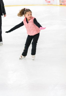 Küçük kız buz pateni pistinde artistik patinaj yapıyor..