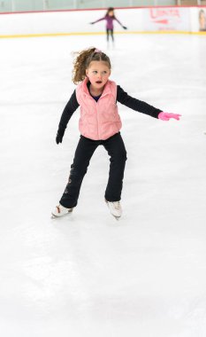 Küçük kız buz pateni pistinde artistik patinaj yapıyor..
