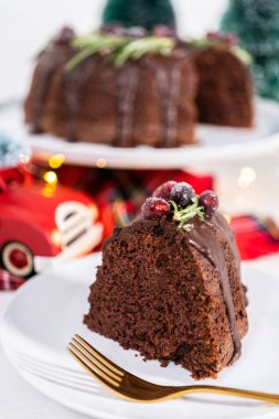 Dilimlenmiş çikolatalı kek taze kızılcıklarla süslenmiş çikolata kremalı ve beyaz şekerle kaplanmış biberiye..