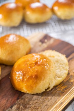 Odun kesme tahtasının üzerinde taze pişmiş çörekleri dilimliyorum..