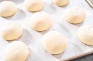 Pişirmeden önce parşömen kağıdıyla kaplanmış fırınlanmış ekmek ruloları..