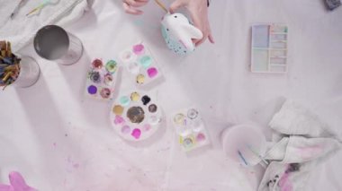 Evde resim dersinde kağıt heykel boyayan küçük bir kız..