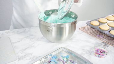 Adım adım. Denizkızı temalı vanilyalı kekler için tereyağlı krema yapmak için mutfak mikserinde malzemeler karıştırılıyor..