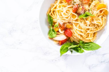 Kiraz domatesli vejetaryen makarna ve beyaz tabakta taze fesleğen..