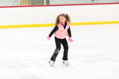 Küçük kız buz pistinde artistik patinaj yapıyor..