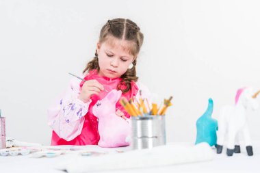 COVID-19 tecridi sırasında evde eğitim. Kağıt mache boyalı küçük kız Akrilik boyalı Paskalya tavşanı biblosu.