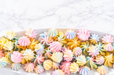 Beyaz servis tabağında çok renkli tek boynuzlu at kurabiyeleri..